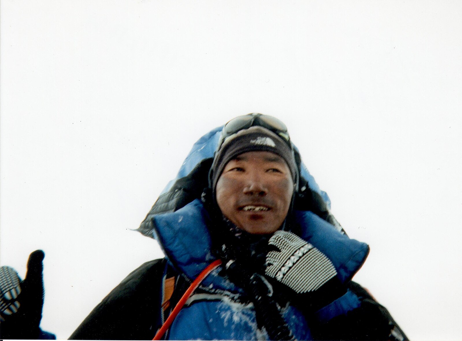 Kami Rita in winter clothing with snow on their gear, standing in a snowy environment.