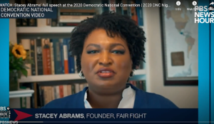 Screenshot of Stacey Abrams on a virtual call sitting in front of a bookshelf