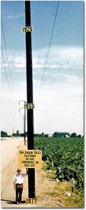 Land subsidence in California - Approximate location of maximum subsidence in the United States identified by research efforts of Dr. Joseph F. Poland (pictured). Signs on pole show approximate altitude of land surface in 1925, 1955, and 1977. The site is in the San Joaquin Valley southwest of Mendota, California.