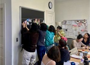 College students hang images on green chalkboard.